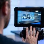 Pro Set monitor displays a modern news studio set, as a person films it.